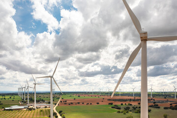 Wind turbine spinning over green farmland, showcasing renewable energy in motion. High angle...