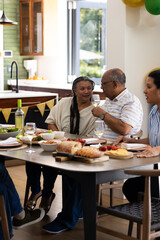 Senior couple enjoying wine and conversation at family gathering in dining room