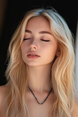 Naklejka premium Close-up portrait of a young woman with long blonde hair and closed eyes expressing calmness and serenity against a dark background