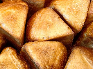 triangular golden brown bread sit closely packed together, showcasing their crispy crusts. warm glow afternoon sun highlights their inviting appearance. closeup.