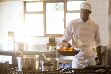 Ingredients are flipping over open flame in black frying pan on gas stove in bright kitchen