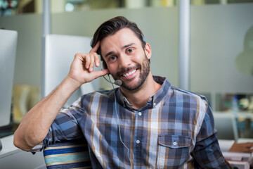 Headset with microphone resting on desk in open-plan office, computer monitor glowing