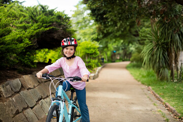 Light blue bicycle is resting on dirt path in park, bordered by stone wall and shrubs