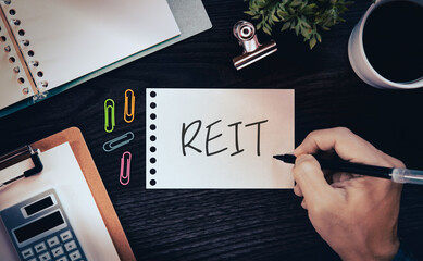 There is notebook with the word REIT. It is an abbreviation for Real Estate Investment Trust as...