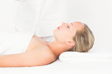 Obraz premium Relaxing woman receiving facial treatment on spa table in spa room, with white towel