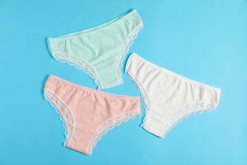 Women's underwear. Beautiful panties on light blue background, flat lay