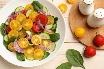 Fresh salad with yellow tomatoes served on wooden table, flat lay