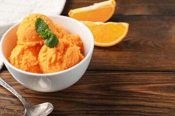 Tasty orange sorbet, fresh fruits and mint on wooden table, closeup