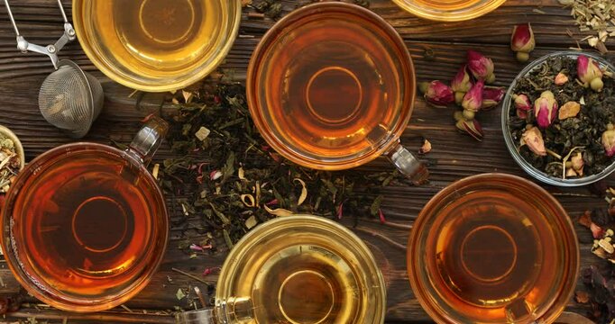 Refreshing herbal tea and dry leaves on wooden table, flat lay