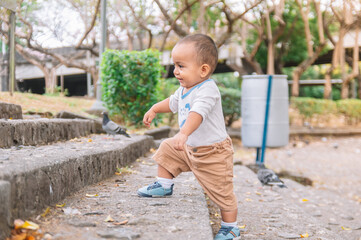 toddler climbing stairs in the park, latin american baby climbs his first steps without help