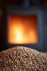 Wood pellets are piled in the foreground with a warm, glowing fire in the background. Sustainable energy and heating concept