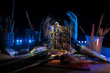 Artistic equipment: empty artist canvas on easel and paint brushes in a artist studio. Retro toned photo.