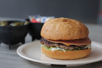 A mouth-watering burger stacked with fresh ingredients and topped with ham, served on a soft sesame seed bun, ideal for satisfying casual dining cravings.