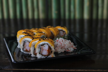 This image showcases a beautifully plated sushi roll, garnished with mayonnaise and black sesame seeds, perfect for food lovers and culinary enthusiasts.