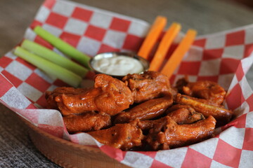 A delicious platter of crispy chicken wings served with fresh celery and carrots, accompanied by a...