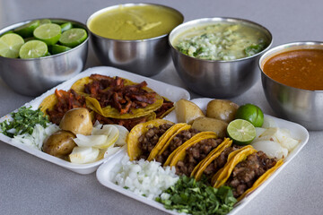 An appetizing arrangement of Mexican tacos accompanied by flavorful sides, including sauces, limes, and potatoes, perfect for capturing the essence of traditional cuisine.