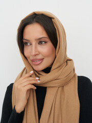 Woman in brown headscarf poses elegantly with warm expression indoors