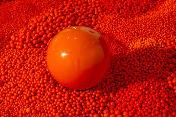 Bright red reflective sphere resting on a textured surface made of small red plastic bead