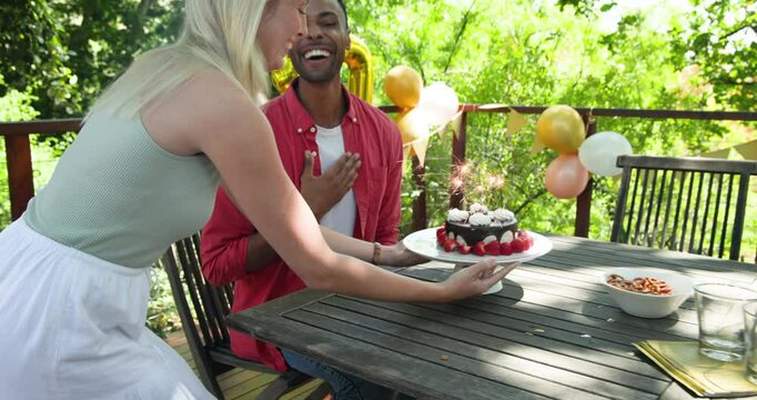 Happy black man and his white female partner celebrating thirtieth birthday, man getting birthday ca
