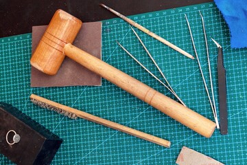 Overhead view on jewelcrafting tools on a green cutting mat in jewelry workplace. 