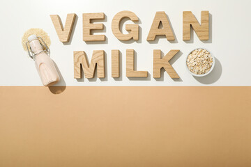 Bottle with milk, sesame seeds, oatmeal and wooden letters on white and beige background, space for...