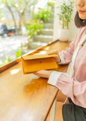 Brown leather wallet in the hands of a girl in a cafe