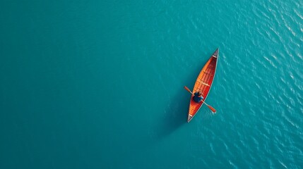Fototapeta premium Serene Aerial View of a Single Canoe Gliding on Clear Turquoise Water Under Bright Sunny Sky