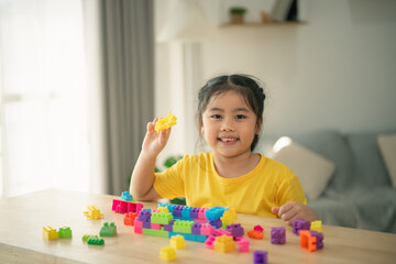 Happy child playing with colorful building blocks in a bright room, fostering creativity and learning through imaginative play during indoor activities