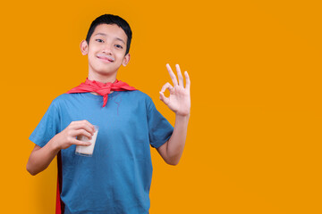 Young Boy Kid Drinking Fresh Tasty Milk and Doing OK Sign with Fingers Isolated on Yellow Background