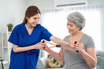 Elderly Asian woman receive physical therapy with support of caregiver. 