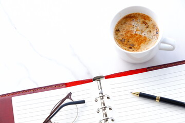 Opened Organizer with Pen and cup of Coffee on Table
