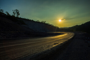A curved road with beautiful backlit sunlight,Asphalt road in the mountains at sunset time. Landscape.
