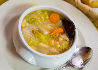 Bean's catalan soup with boiled carrots and potatoes , served with black sausage in bowl