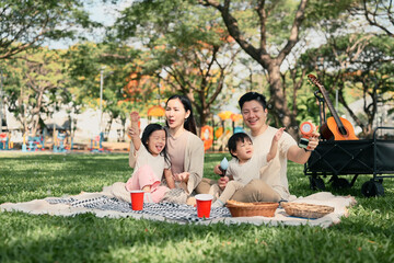 Happy family having a picnic and playing with bubbles together at the park