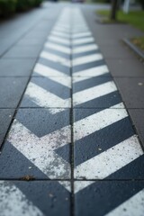 A perspective view of a pavement with a distinctive chevron pattern, showcasing the texture and detail of the painted markings on the paving stones.
