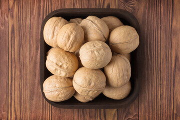 shelled walnut, chilean in square plate on wooden table background. vegetarian organic food for healthy diet.