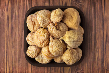 dried figs in square plate on wooden table background. vegetarian organic food for healthy diet.