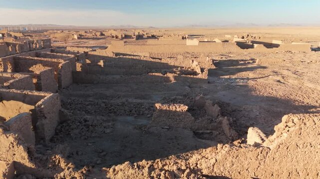 Close-up drone shot of the ruined adobe facades of a former saltpeter works, close flight moving forward into the sunset in the desert