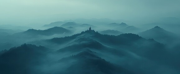 Naklejka premium Blue-tinted misty mountains view with a building atop the highest point