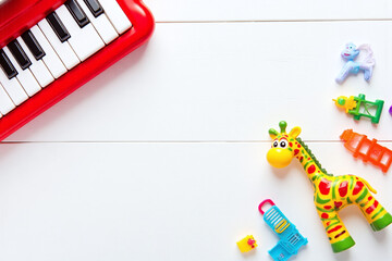 baby toy giraffe and a toy piano on a white wooden surface