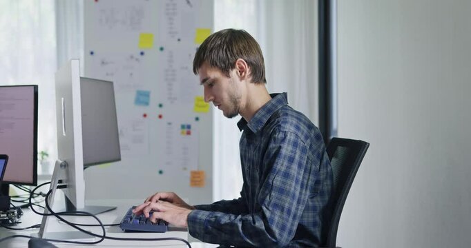 Portrait confident smiling male programmer working with robotics code AI software and looking at camera in tech office. Artificial intelligence dashboard, robotics, user interface, machine learning.