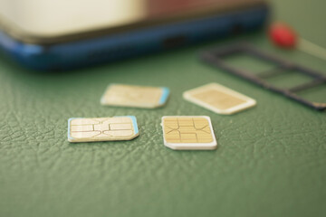 Fototapeta premium Different sizes of SIM cards next to a smartphone on green background