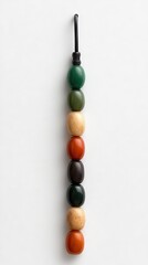 Colorful bead string. Stacked shades of green, brown, and red on cord. Minimalist design
