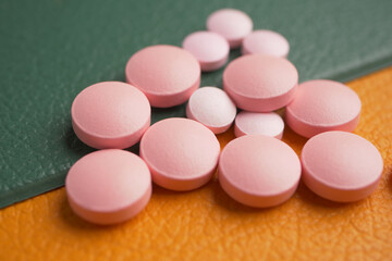 Pink round tablets resting on textured surfaces in a medical setting