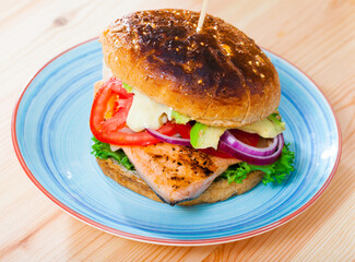 Delicious fish burger with juicy trout fillet, vegetables and avocado