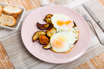 Fried sunny side up eggs with sliced eggplant for lunch in canteen. Public catering ovo-vegetarian food concept..