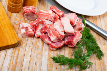 Chopped raw pork ribs placed on table with dill.
