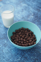 Chocolate cereal in a blue bowl with milk on a blue background