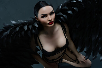 Woman in alluring lingerie with striking black wings poses gracefully