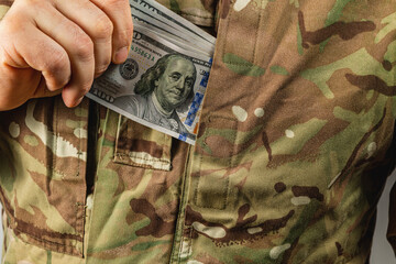 Soldier discreetly tucking money into camouflage pocket